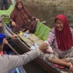 Sambangi Warga yang Terjebak Banjir, Polres Kubar Dayung Perahu Antar Daging Kurban